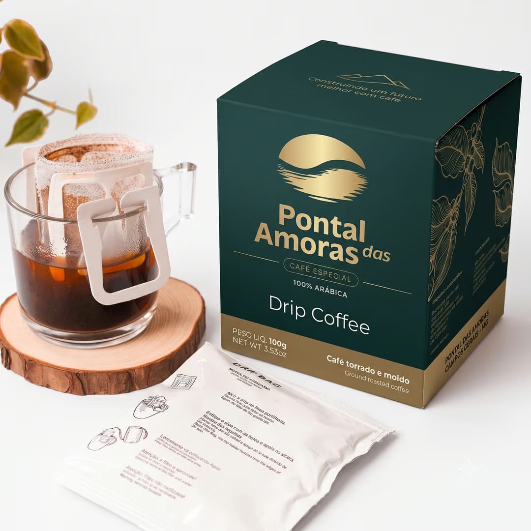 Caixa de drip coffee Pontal das Amoras de 100 g, ao lado de um sachê e de uma xícara em preparo.